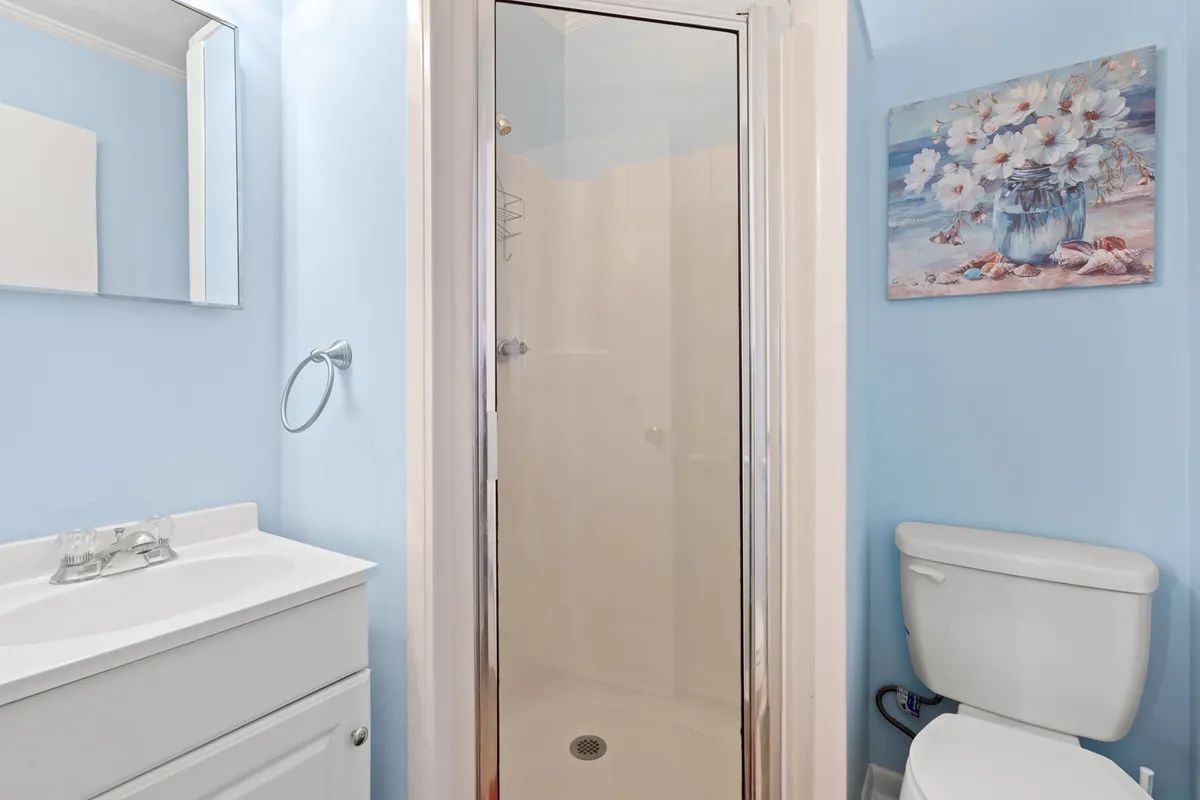 A modern en suite bathroom with a glass shower stall, a sleek vanity sink, and decorative floral artwork. The space exudes calm, ideal for refreshing showers and quiet personal routines.