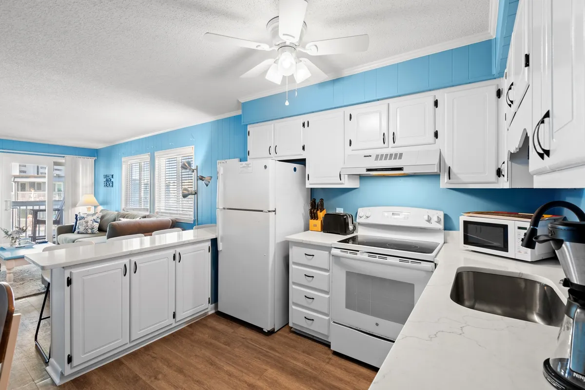 A bright, open kitchen featuring modern appliances, cheerful blue walls, and a spacious dining bar. The setup is inviting for family gatherings, casual dining, or prepping meals together, with all the essentials clearly visible.